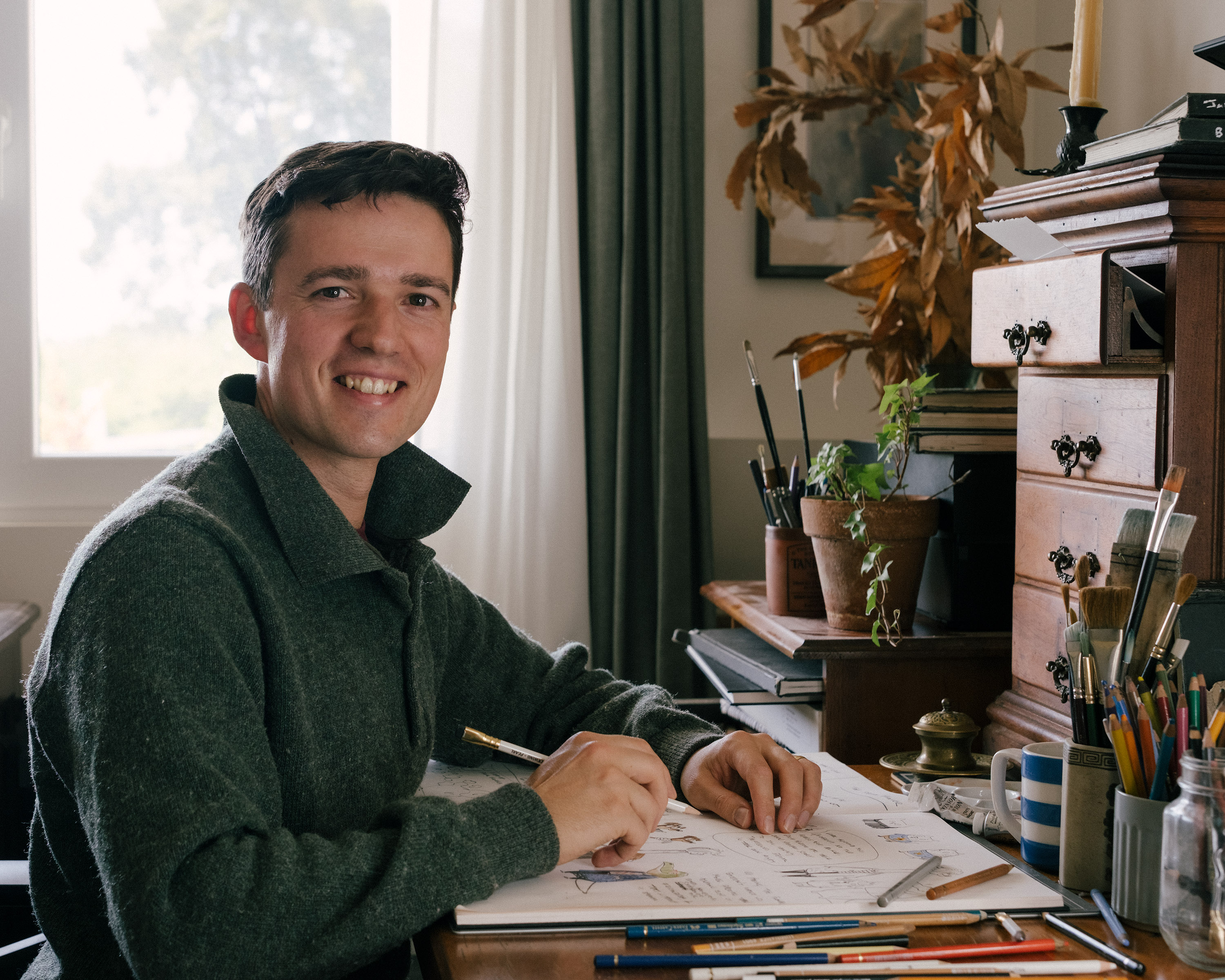 Photo of Gabriel Evans sitting at his desk drawing in a sketchbook.